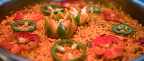 A large metal cooking pot filled with rice and sliced jalapeños.