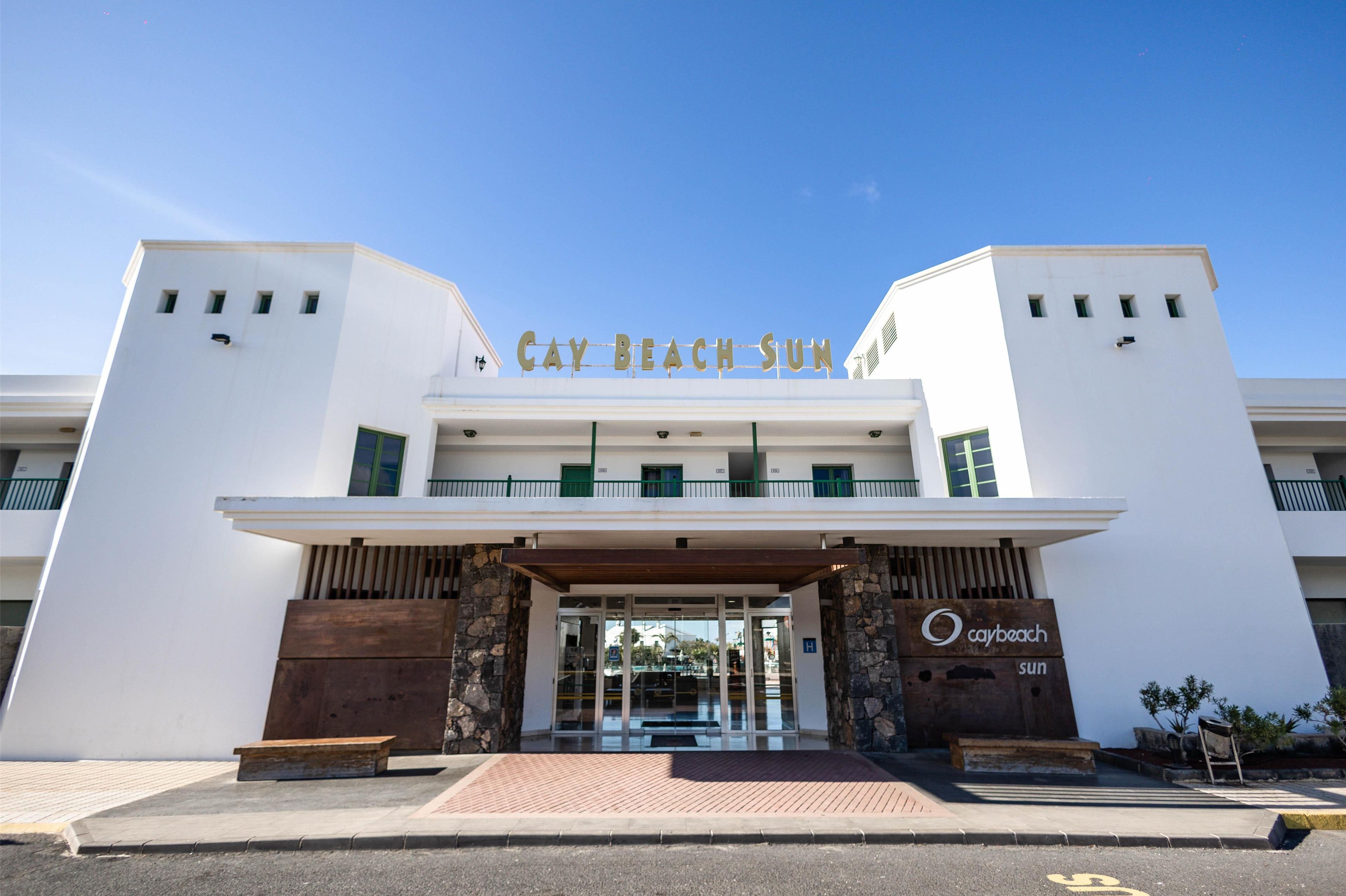 Una entrada moderna de hotel con un letrero claro que dice 'Cay Beach Sun'.