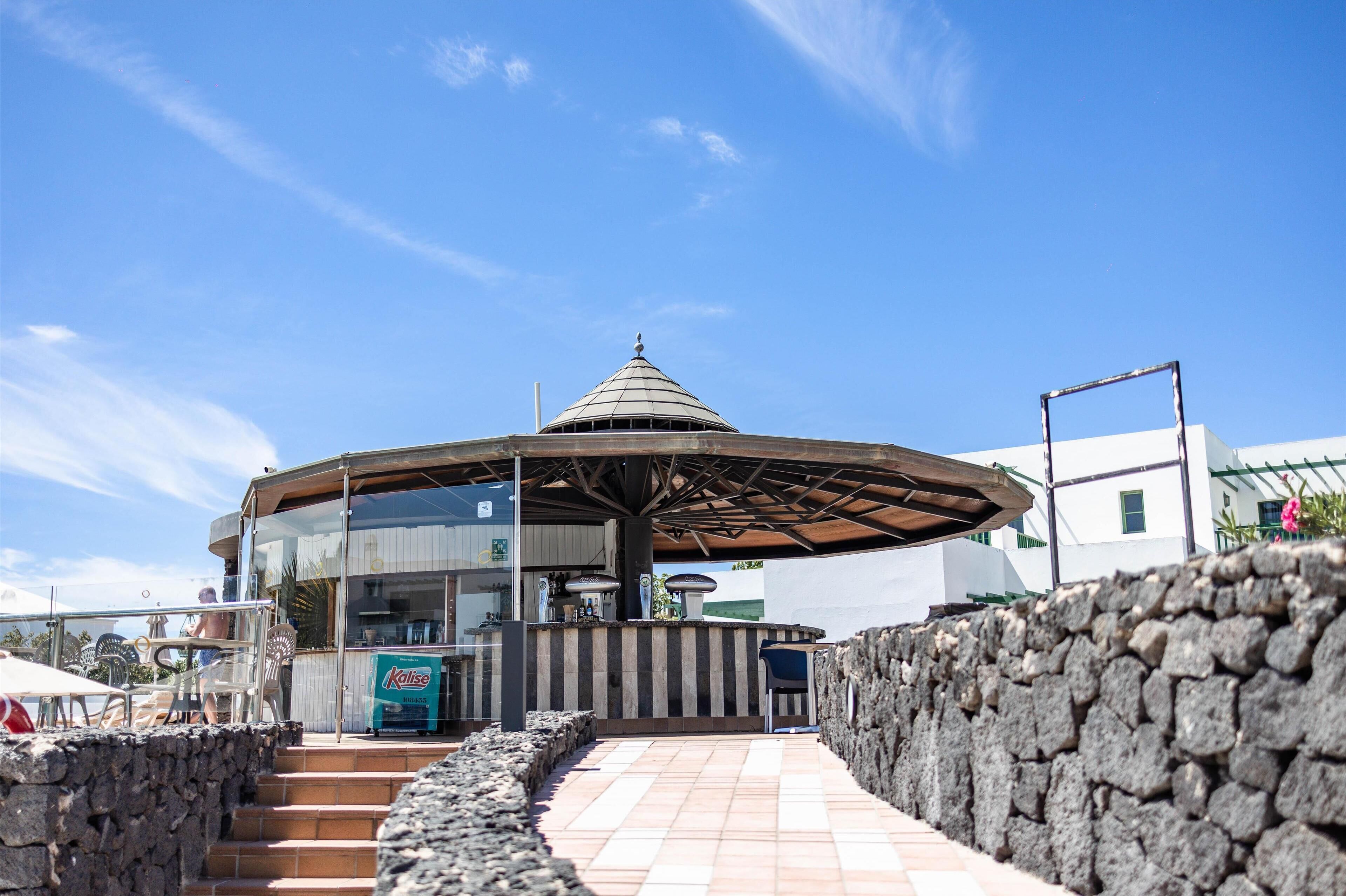 A modern outdoor seating area with a stone wall and a glass structure.