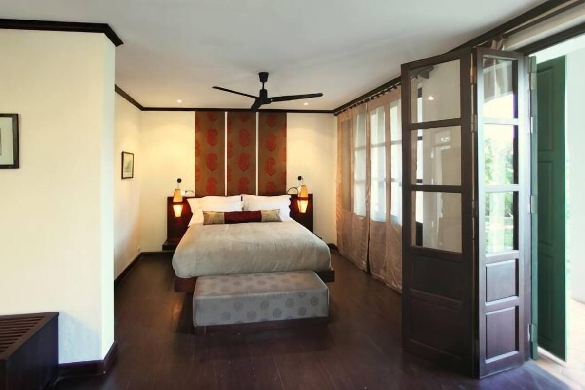 A bedroom with a bed, bedside tables, a ceiling fan, and a large window.