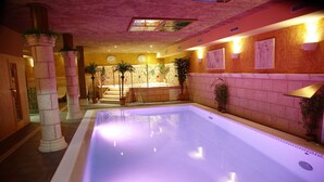 An indoor swimming pool with a tiled floor, surrounded by stone pillars and potted plants. - Posada Spa Privilegio de Vara (Noja)