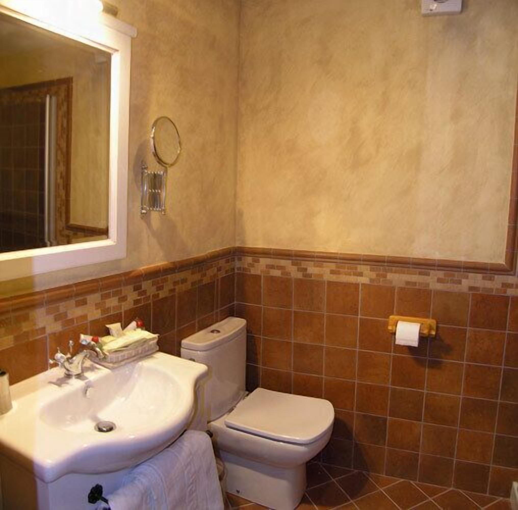Een badkamer met een wastafel, toilet en spiegel.