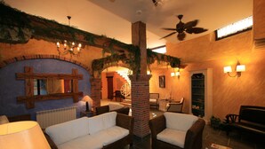 A cozy living area with wicker sofas, a fireplace, and a ceiling fan. - Posada Spa Privilegio de Vara (Noja)