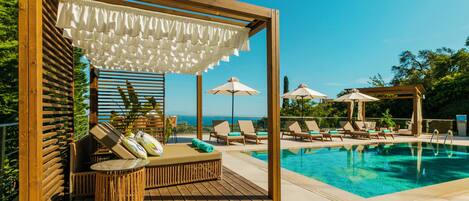 A wooden deck with a pool, lounge chairs, and umbrellas.