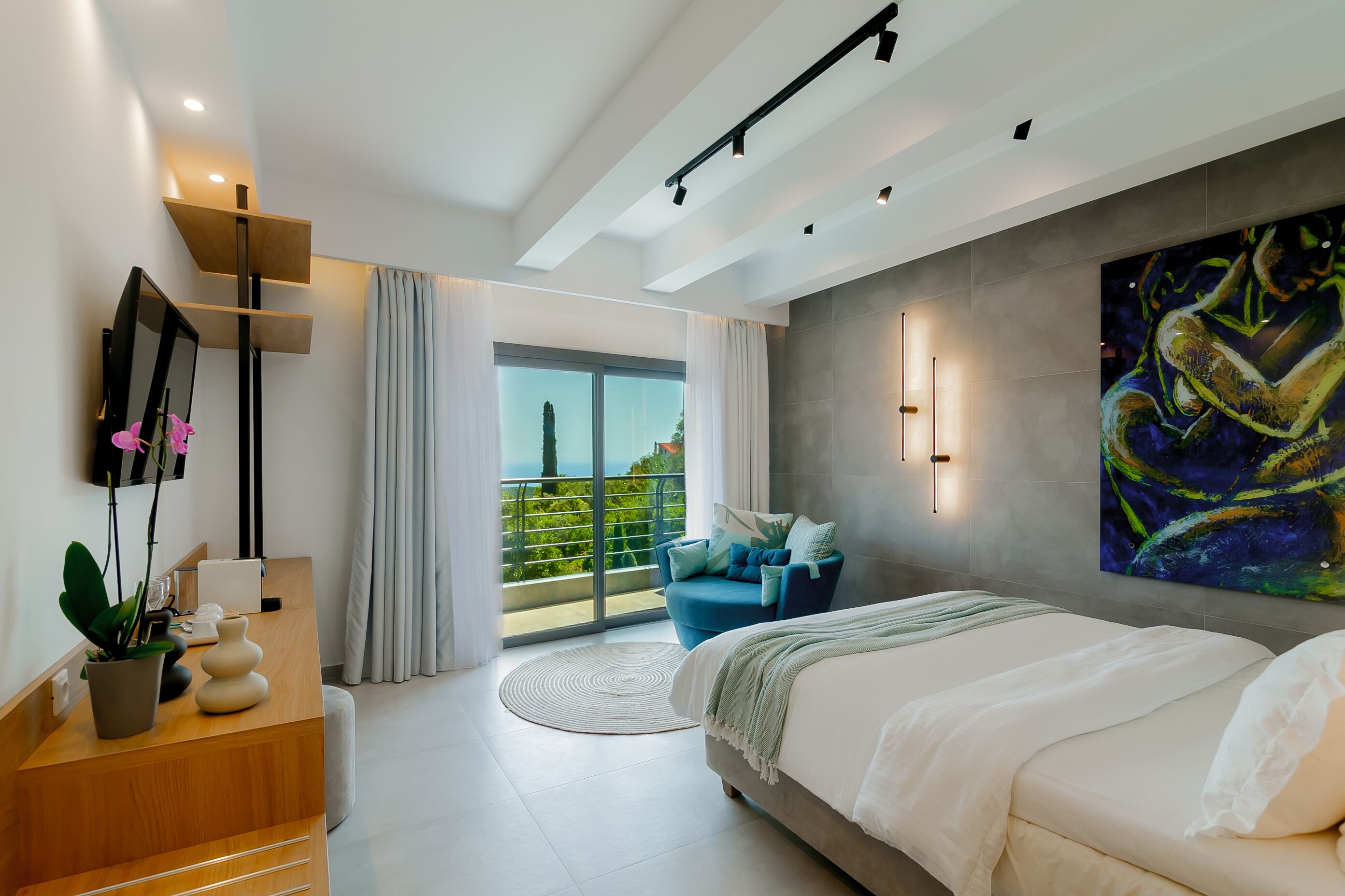 A modern bedroom with a large bed, a desk with a potted plant, a chair, and a balcony with a view.