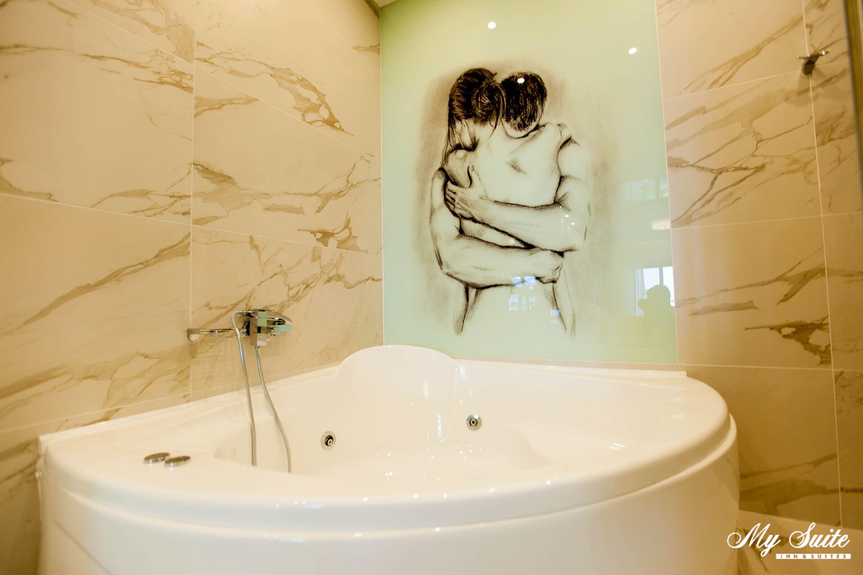 A bathroom with a large bathtub, marble walls, and a mural of two people embracing.