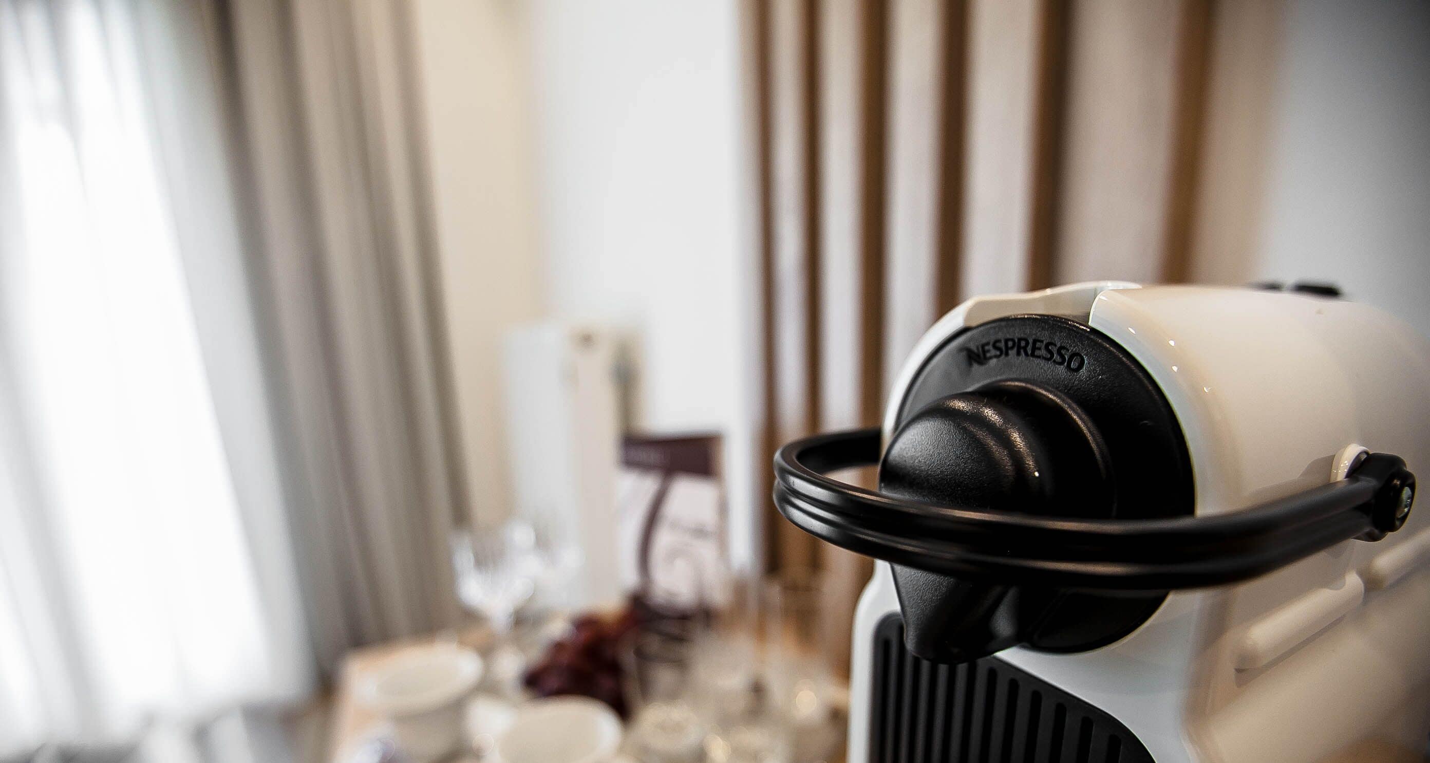 A close-up of a Nespresso coffee machine with a blurred background of a dining area.