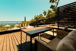 A wooden deck with a table and chairs, overlooking a scenic view of the sea and greenery. - My Suite (Parga)