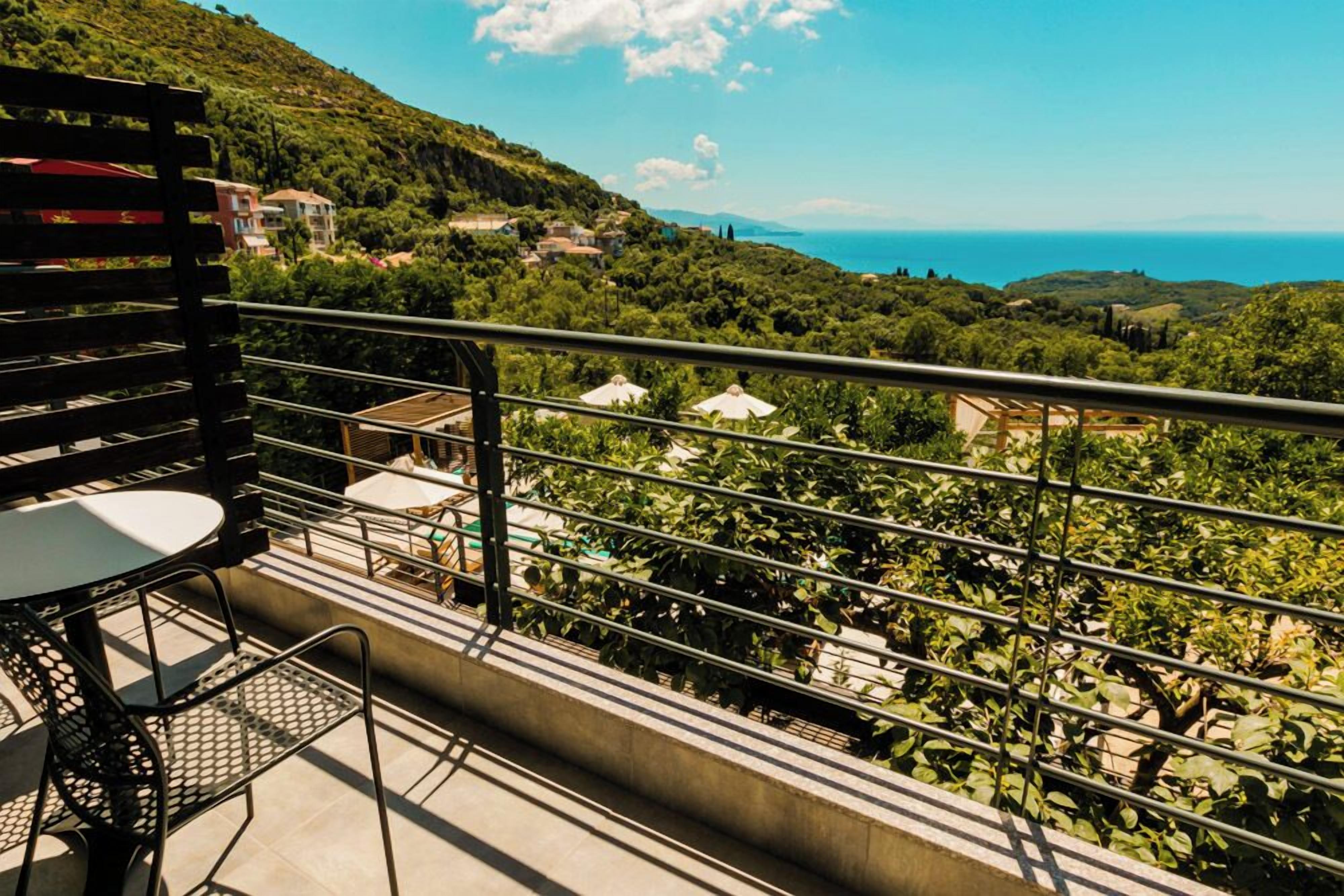 A balcony with a table and chairs overlooking a scenic coastal landscape.