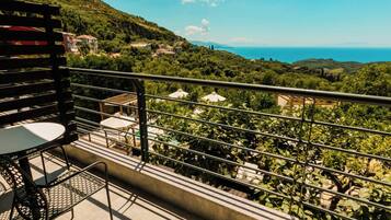 A balcony with a table and chairs overlooking a scenic coastal landscape.