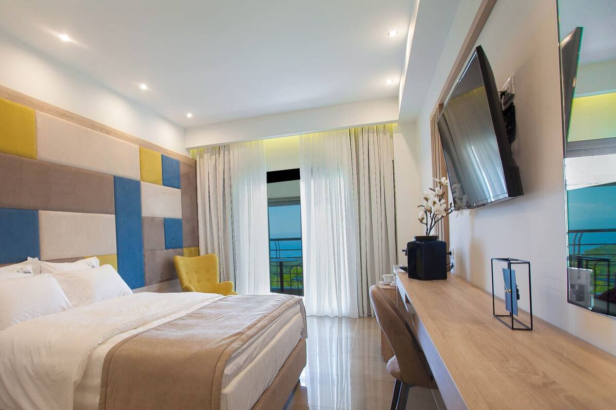 A modern hotel room with a large bed, a desk, and a TV mounted on the wall.