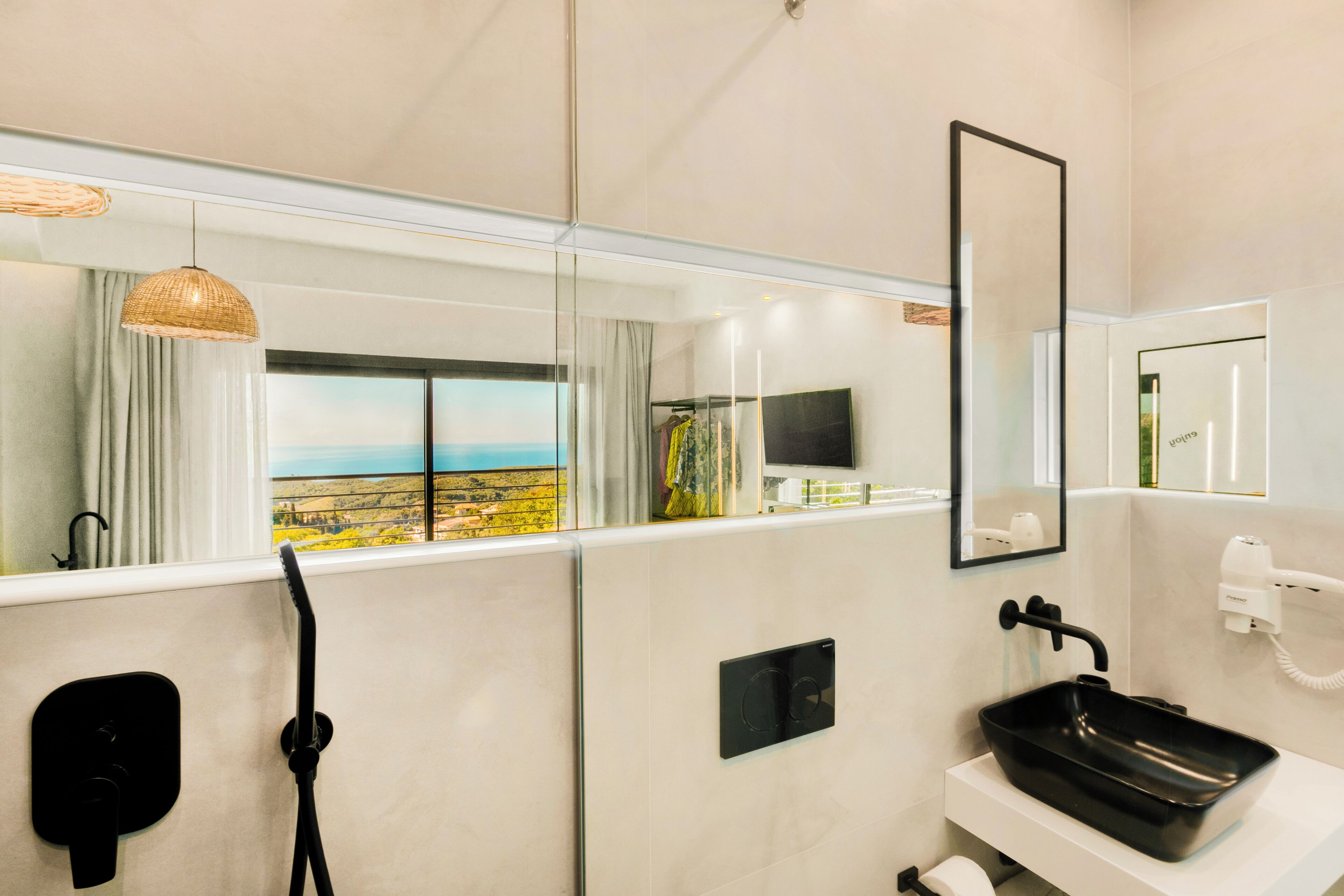 A modern bathroom with a large mirror, a black sink, a shower, and a view of the outdoors through a window.