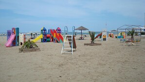 Una playa con estructuras de juego coloridas, una escalera y una palmera pequeña.