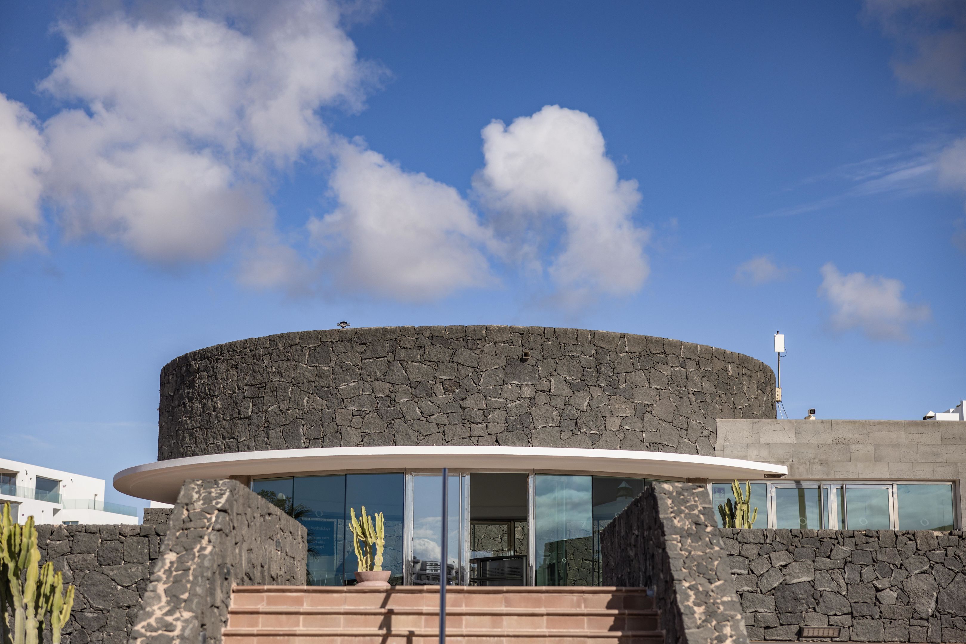A modern building with a curved glass entrance and a stone facade.