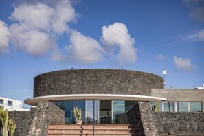 Un bâtiment moderne doté d’une entrée en verre incurvé et d’une façade en pierre.