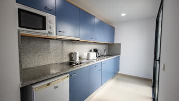 Una cocina con armarios azules, microondas, cafetera y lavavajillas.