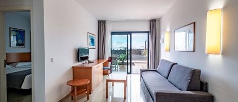 A hotel room with a bed, a desk, a sofa, and a view of the outdoors.