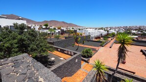 A residential area with modern architecture, a clear sky, and a mountain in the background. - Caybeach Papagayos (Yaiza)