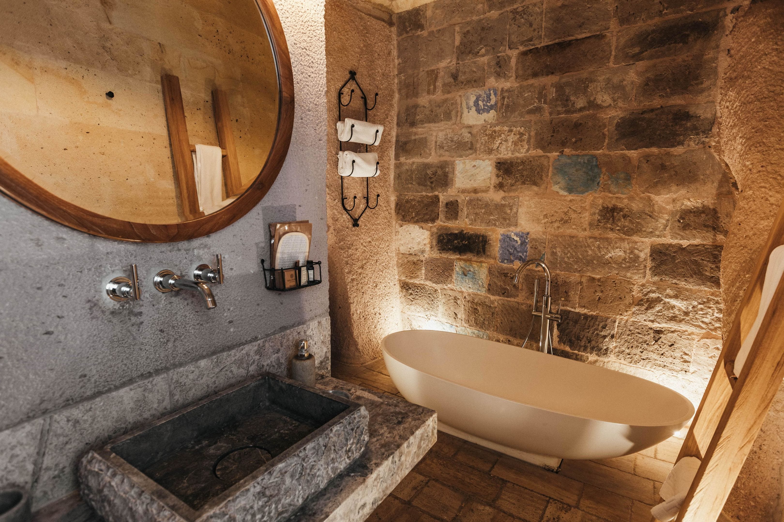 A bathroom with a freestanding bathtub, a large mirror, and a stone sink.