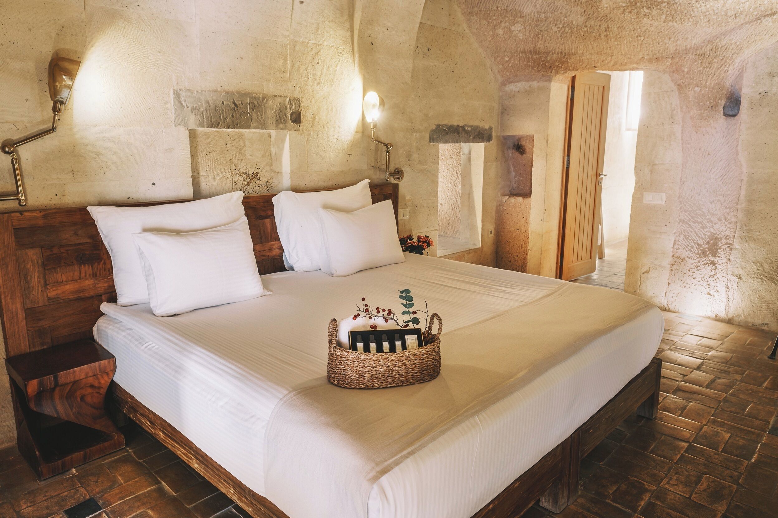 A bedroom with a large bed, wooden headboard, and a bedside table.