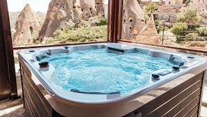 A hot tub with a view of rock formations and buildings. - Millstone Cave Suites (Nevsehir)