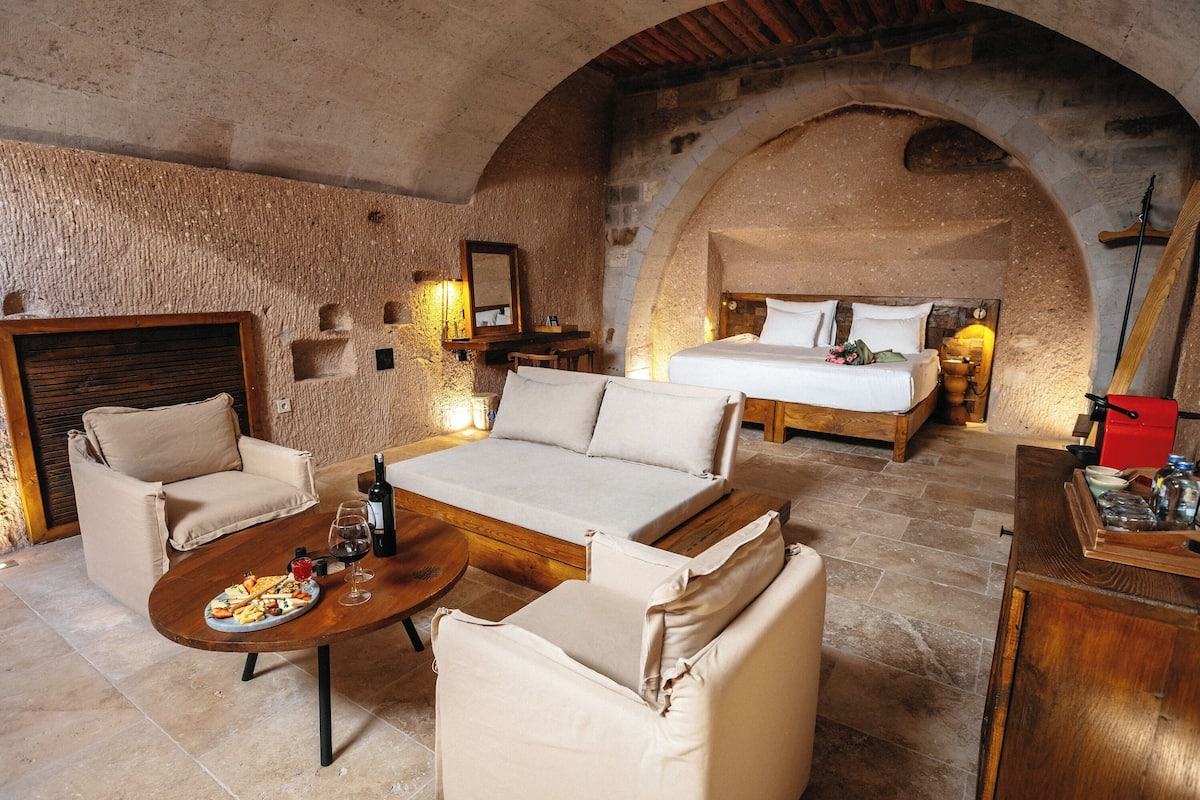 A cozy room with a sofa, a dining table with food, a bed, and a wooden cabinet.