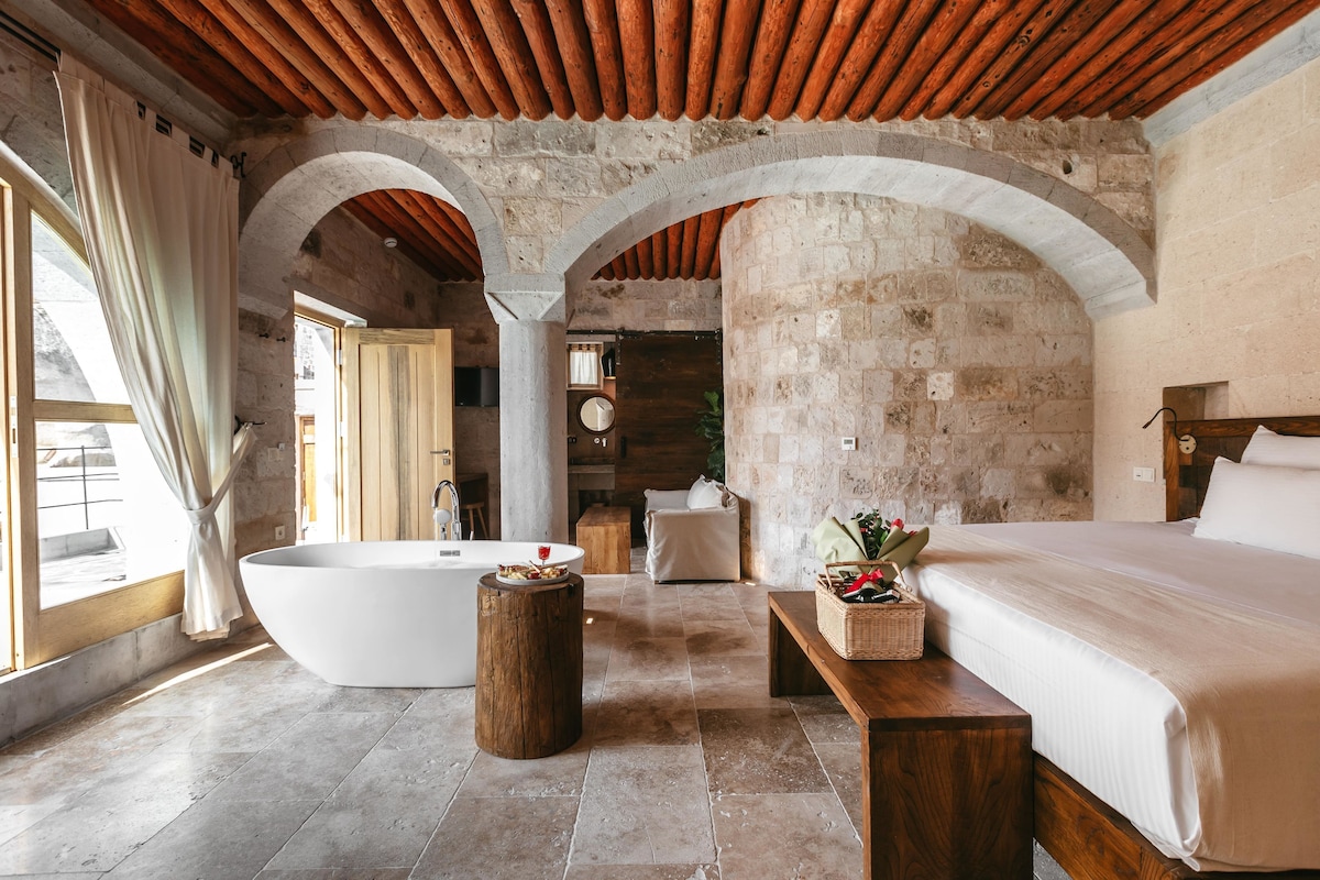 A spacious room with a large bathtub, a wooden bench, and a bed.