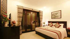 Une chambre d’hôtel avec un grand lit, une armoire avec un miroir, une table de chevet avec une lampe et un tableau au mur.