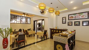 A restaurant with tables and chairs, a buffet counter, and ceiling fans. - Pham Gia Boutique Villa (Da Nang)