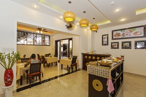 Un restaurant avec des tables et des chaises, un buffet et des ventilateurs de plafond.