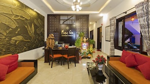 A hotel lobby with a reception desk, seating area, decorative wall, and a staircase in the background. - Pham Gia Boutique Villa (Da Nang)