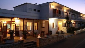 A two-story building with a balcony on the upper floor, a stone pathway leading to the entrance, and outdoor lighting. - Hotel Artemon (Sifnos)