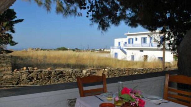 A table set outdoors with a view of a white building and a stone wall. - Hotel Artemon (Sifnos)