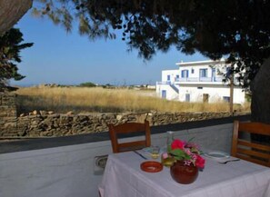 A table set outdoors with a view of a white building and a stone wall. - Hotel Artemon (Sifnos)