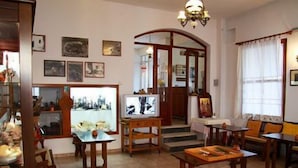 A cozy living room with a television, wooden furniture, and artwork on the walls. - Hotel Artemon (Sifnos)