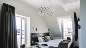 Una habitación de hotel moderna con una cama grande, una mesa de comedor y vistas a la ciudad.