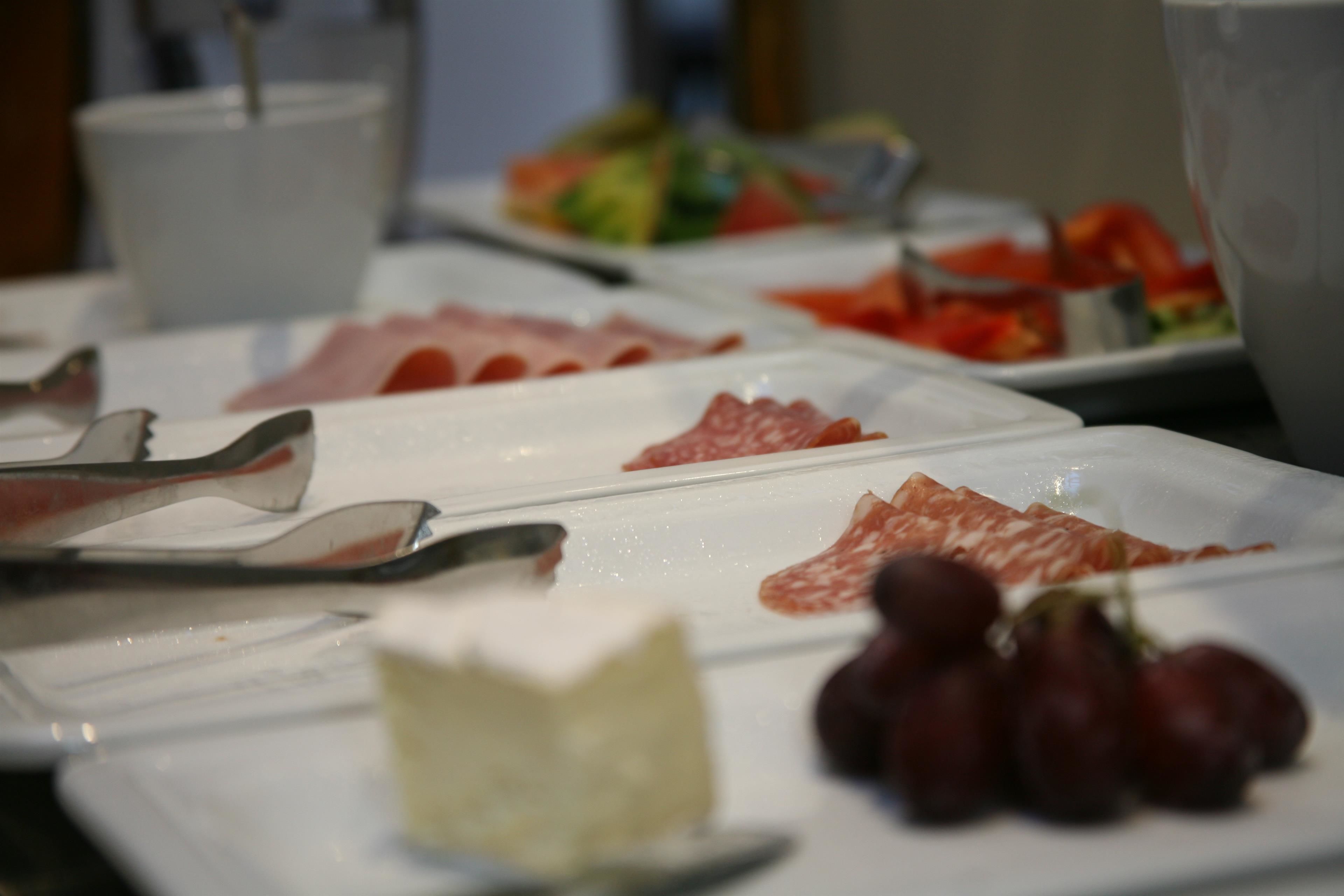 A buffet with various food items including meats, cheese, and grapes.