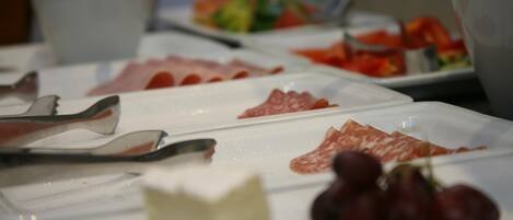 A buffet with various food items including meats, cheese, and grapes.