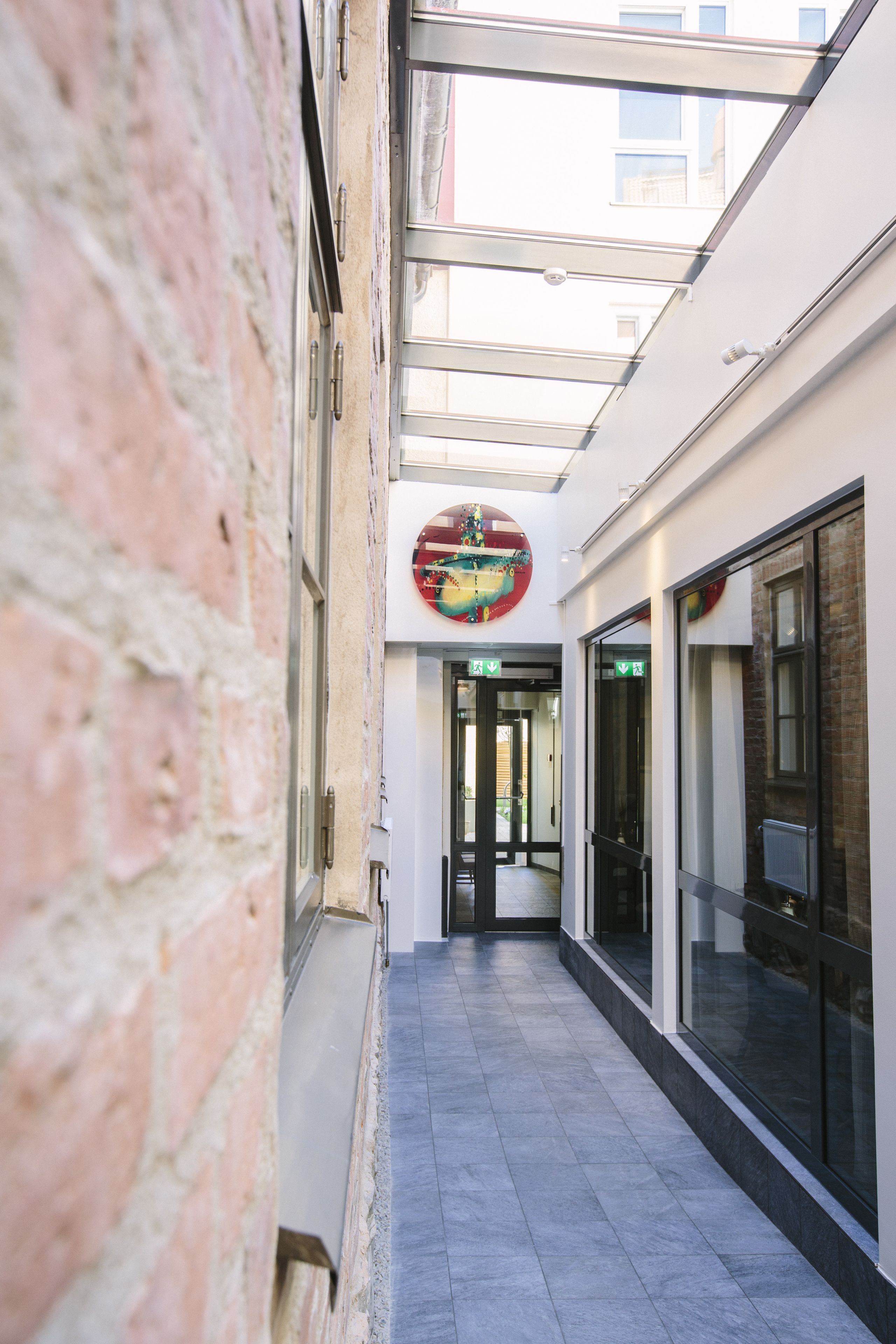 A corridor with a skylight, glass doors, and a circular sign on the wall.