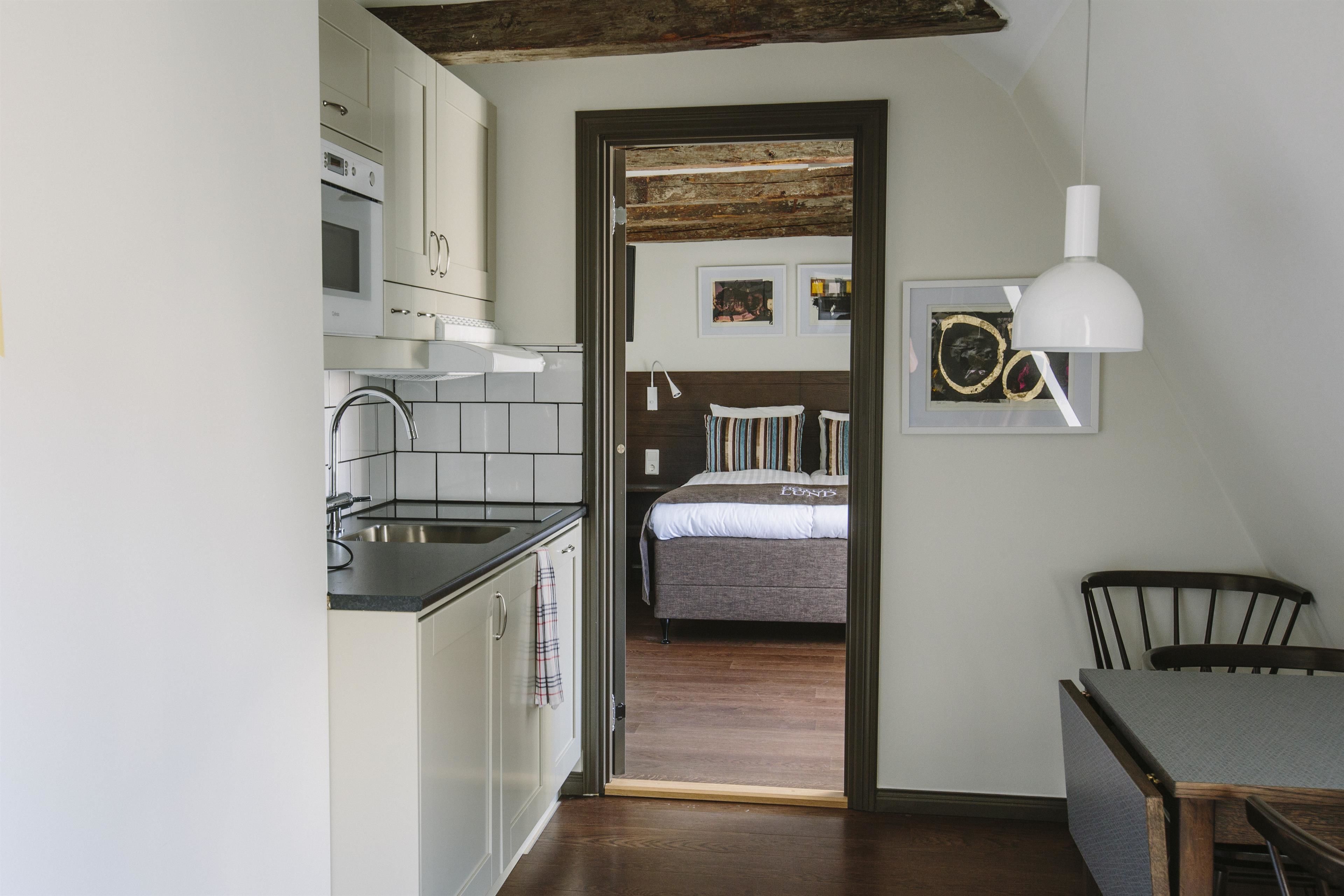 A compact kitchen with white cabinets, a modern stove, and a dining area with a table and chairs.