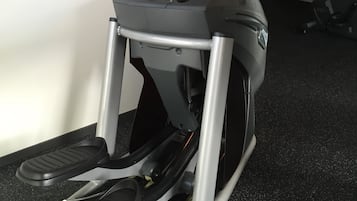 Een hometrainer met een digitaal display en bedieningspaneel, op een vloer met tapijt.