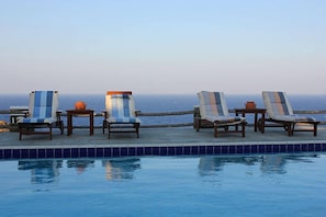 Een buitenzwembad, ligstoelen bij het zwembad