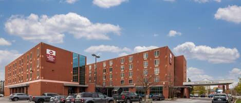 A hotel with a brick facade, multiple parking spaces, and a clear sky.