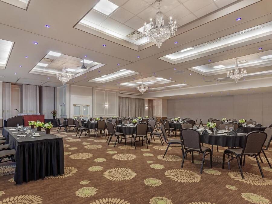 Une salle de conférence équipée de tables, de chaises, d’un pupitre et d’un lustre.