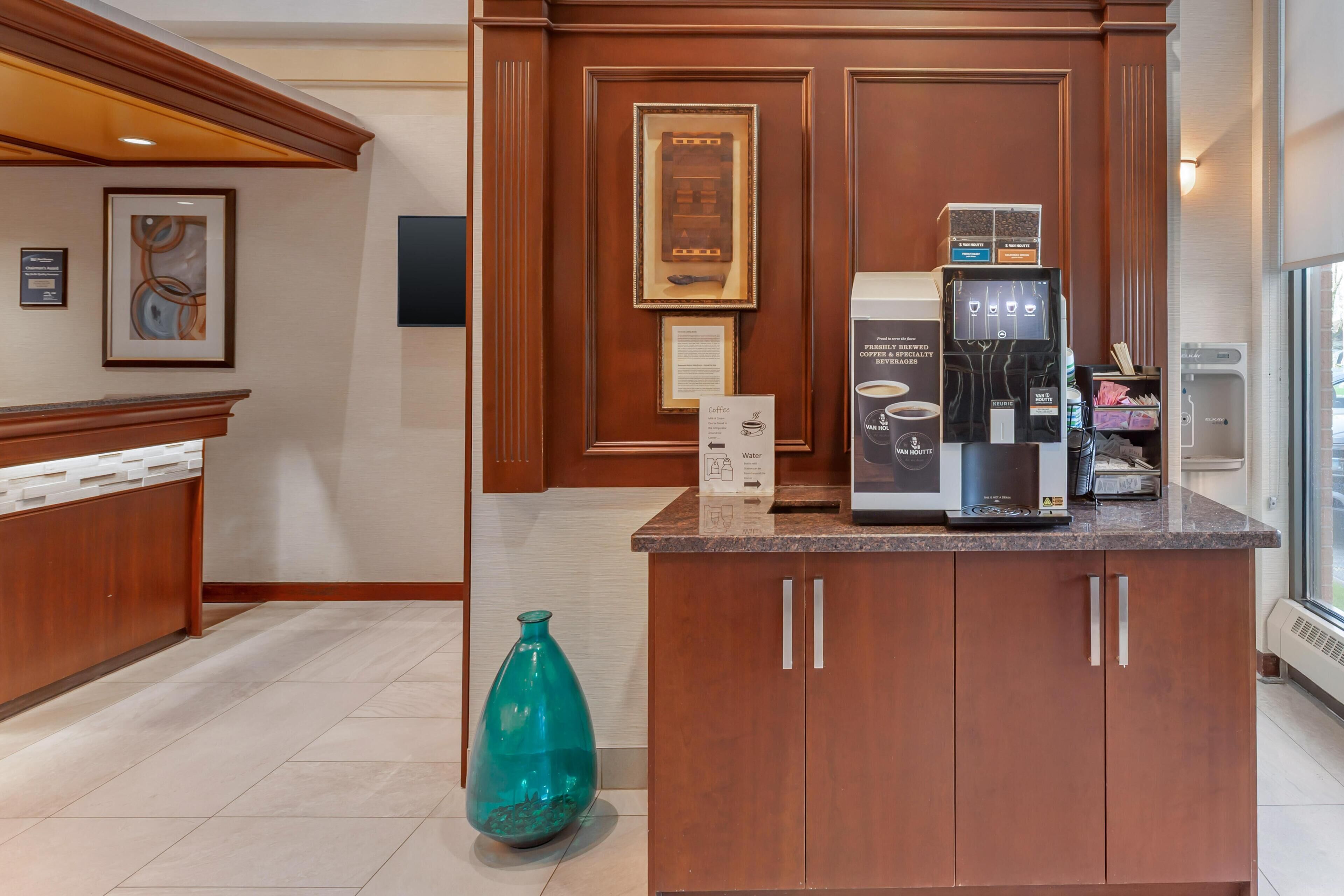 A modern kitchen with a coffee machine, a water dispenser, and a teal vase on the counter.