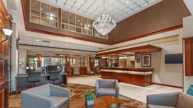 Een ruime lobby met een hoge plafond, een kroonluchter en een receptiebalie.