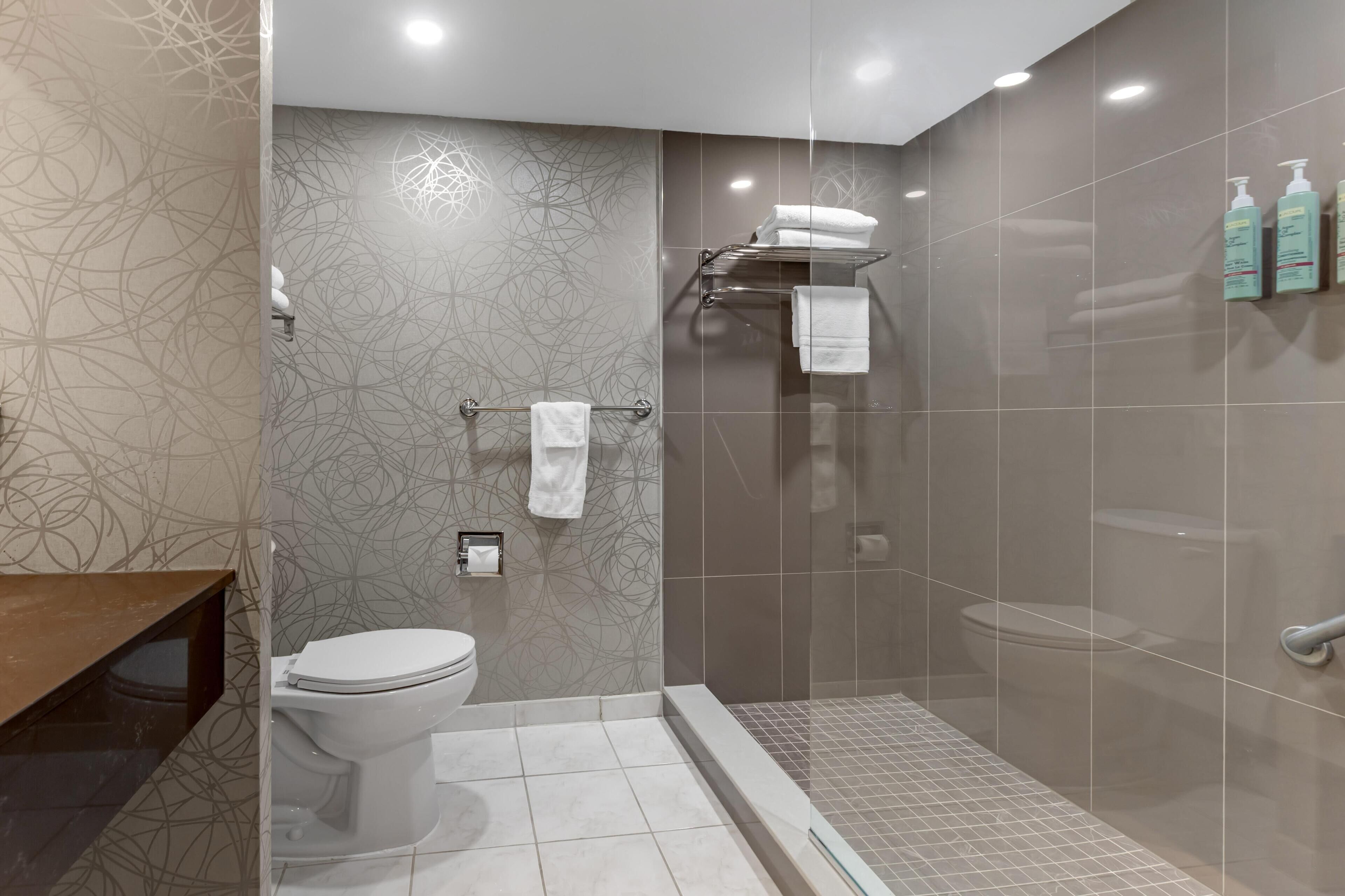 Ein modernes Badezimmer mit Toilette, Duschbereich und einer Glaskabine für die Dusche.