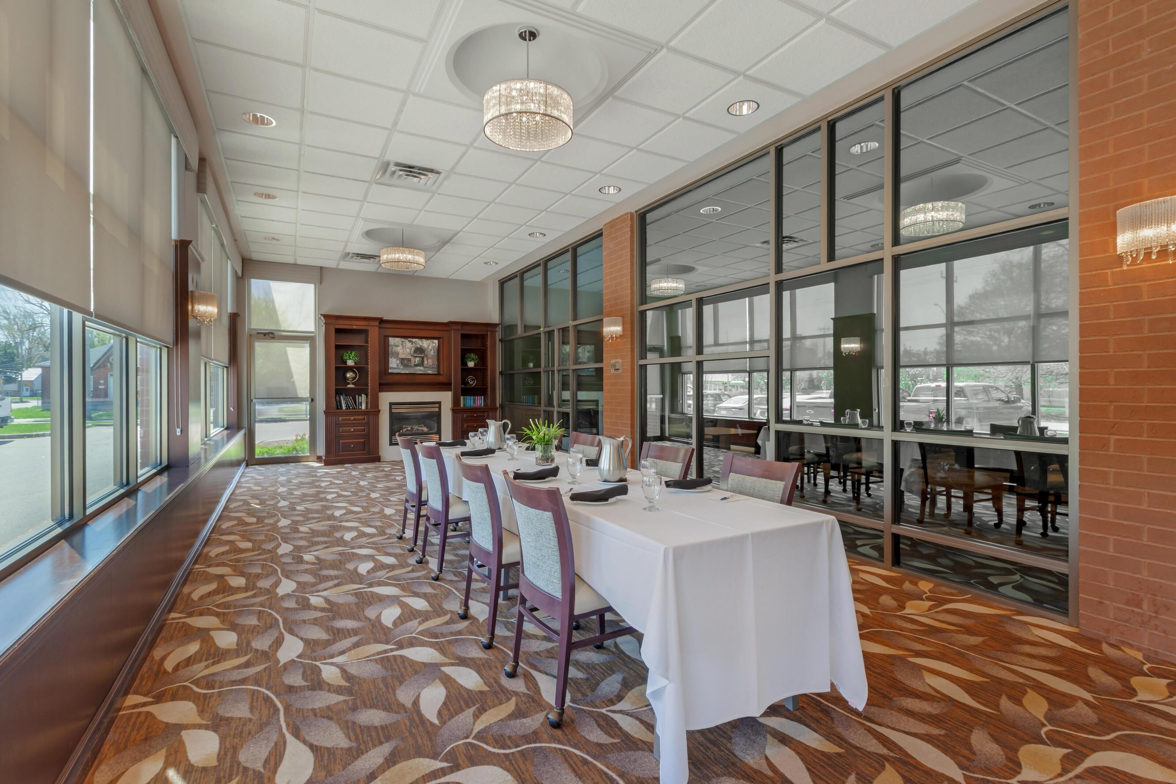 A spacious dining area with a long table, chairs, and a patterned carpet.