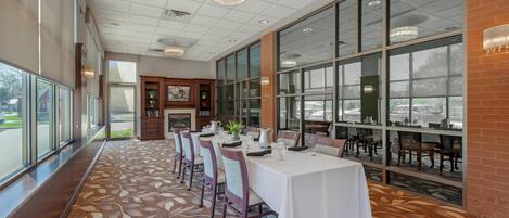 A spacious dining area with a long table, chairs, and a patterned carpet.