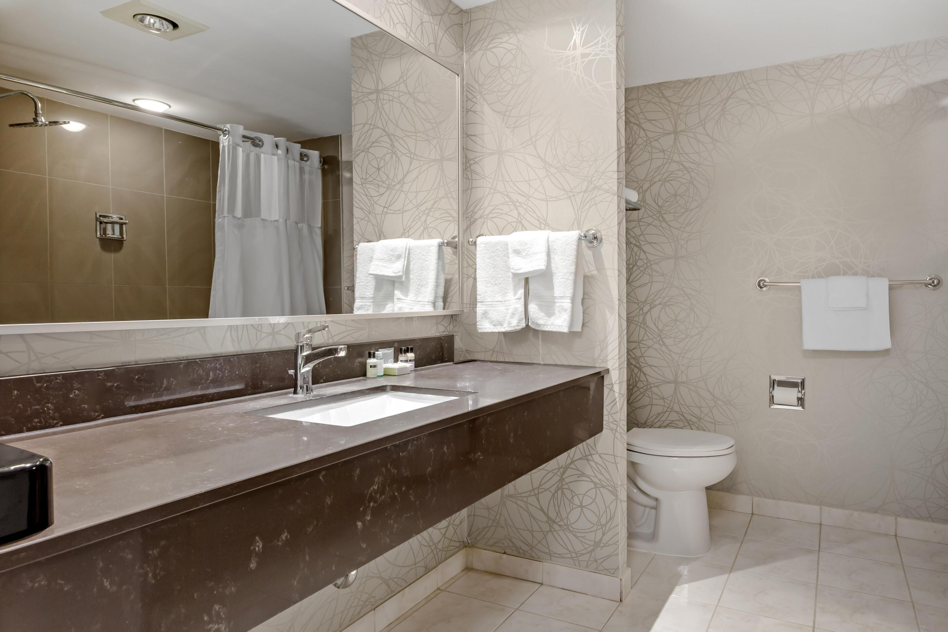 A modern bathroom with a marble vanity, a shower, and a toilet.